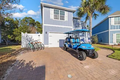 a golf cart parked in front of a house with bikes at Beach Bliss in Inlet Beach