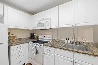 a white kitchen with white cabinets and a sink at Grandy 30A in Inlet Beach