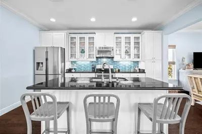 a kitchen with a counter with chairs and a refrigerator at Inlet Love in Inlet Beach