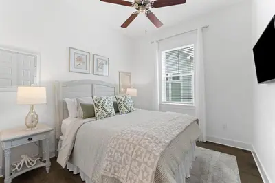 a white bedroom with a bed and a ceiling fan at Heron's Nest in Inlet Beach