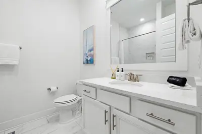 a white bathroom with a toilet and a sink at Heron's Nest in Inlet Beach