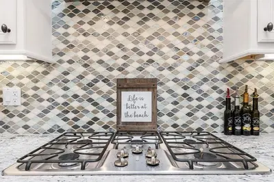 a kitchen counter with a stove top with wine bottles at Lucky Beach in Inlet Beach