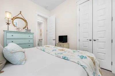 a bedroom with a white bed with a blue dresser and a mirror at Lucky Beach in Inlet Beach