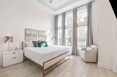 a white bedroom with a bed and a chair at Amen 30A in Inlet Beach