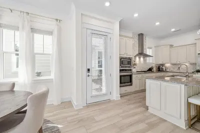 a kitchen with white cabinets and a table and chairs at Amen 30A in Inlet Beach