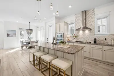 a kitchen with white cabinets and a island with bar stools at Amen 30A in Inlet Beach