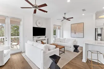 a living room with white furniture and a flat screen tv at Journey to 30A in Inlet Beach