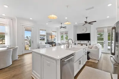 a kitchen and living room with white cabinets and a tv at Journey to 30A in Inlet Beach