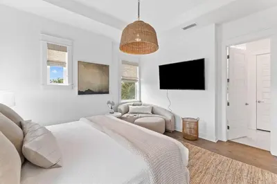 a white bedroom with a bed and a tv at Journey to 30A in Inlet Beach