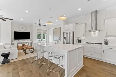 a kitchen with white cabinets and a kitchen island with bar stools at Journey to 30A in Inlet Beach