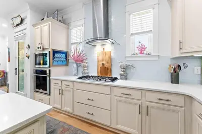 a kitchen with white cabinets and a stove top oven at Coco Cottage in Inlet Beach