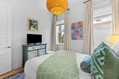 a bedroom with a bed and a flat screen tv at Coco Cottage in Inlet Beach