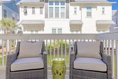two wicker chairs on a balcony with a house in the background at Lala's Beach House in Inlet Beach