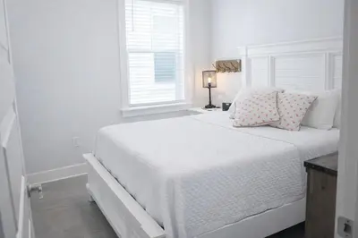 a white bedroom with a white bed with pillows and a window at Beachwood Hideaway in Inlet Beach