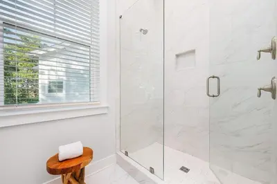 a bathroom with a glass shower with a wooden stool at Forever Grateful in Inlet Beach