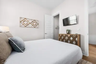 a white bedroom with a bed and a television at Forever Grateful in Inlet Beach