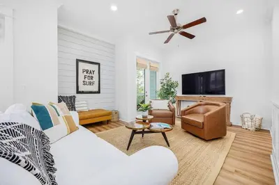 a living room with a white couch and a flat screen tv at Sea'n is Believe'n in Inlet Beach