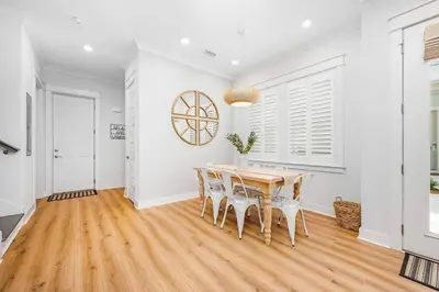 a dining room with a wooden table and white walls at Sea'n is Believe'n in Inlet Beach