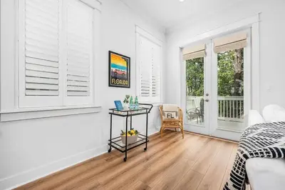 a bedroom with white walls and a table and windows at Sea'n is Believe'n in Inlet Beach