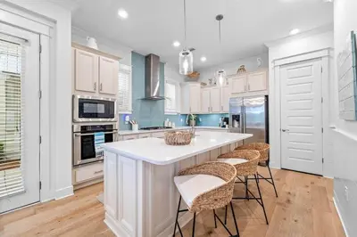 a kitchen with white cabinets and a white island with stools at Just Beachy in Inlet Beach