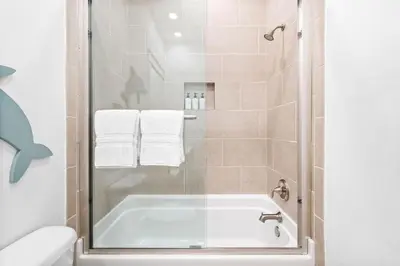 a bathroom with a tub and a shower with towels at Just Beachy in Inlet Beach