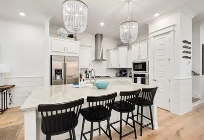 a kitchen with white cabinets and a island with bar stools at Time & Tide 30A in Inlet Beach