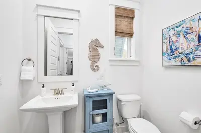 a bathroom with a sink and a toilet and a mirror at Time & Tide 30A in Inlet Beach