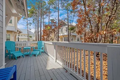 a deck with blue chairs and tables on a house at Time & Tide 30A in Inlet Beach