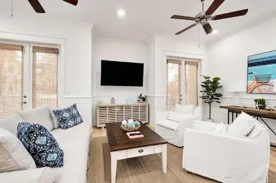 a living room with white furniture and a flat screen tv at Time & Tide 30A in Inlet Beach