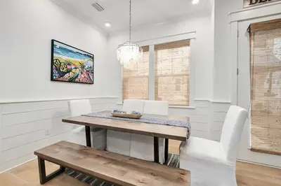 a dining room with a wooden table and white chairs at Time & Tide 30A in Inlet Beach