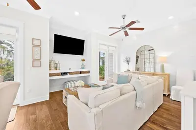 a white living room with a white couch and a tv at Skippy's Hideaway in Inlet Beach