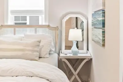a white bedroom with a bed and a mirror at Skippy's Hideaway in Inlet Beach