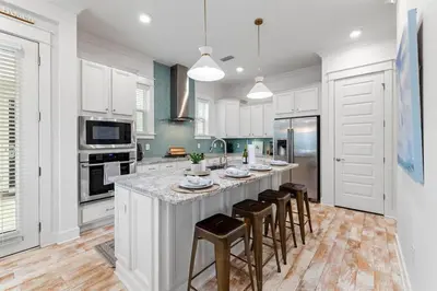 a kitchen with white cabinets and a large island with bar stools at License to Chill in Inlet Beach