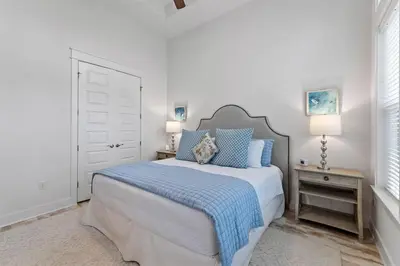 a white bedroom with a bed with blue pillows at License to Chill in Inlet Beach