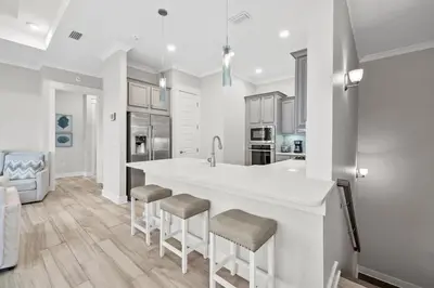 a kitchen with a large white counter and stools at Isle be 'SEA'ing You in Inlet Beach