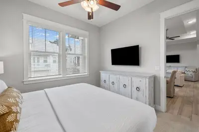 a white bedroom with a bed and a flat screen tv at Isle be 'SEA'ing You in Inlet Beach