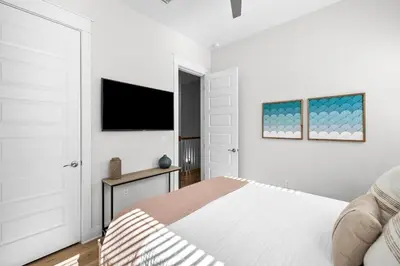 a white bedroom with a bed and a flat screen tv at BeachHaven 30A in Inlet Beach