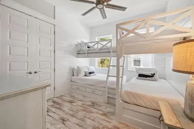 a white bedroom with a bunk bed and a desk at Sand Dollar Dream in Inlet Beach