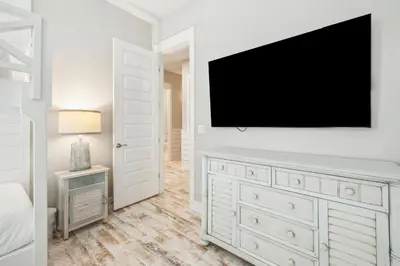 a bedroom with a dresser with a tv on a wall at Sand Dollar Dream in Inlet Beach