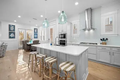 a kitchen with white cabinets and a island with bar stools at Doc's House in Inlet Beach