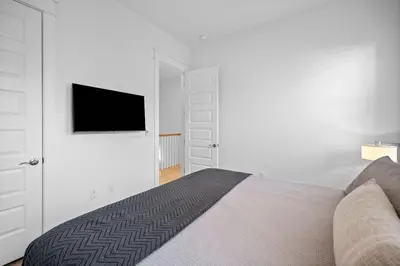 a white bedroom with a bed and a flat screen tv at Doc's House in Inlet Beach