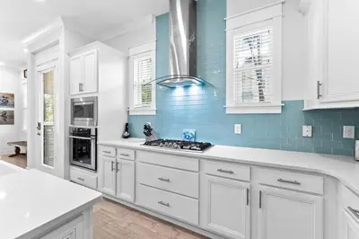 a kitchen with white cabinets and blue tiles at SaltLife30A in Inlet Beach