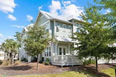 a white house with a porch and trees at Surfers Retreat in Inlet Beach