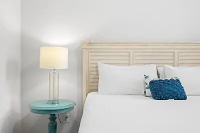 a bed with a blue nightstand next to a blue lamp at Serenity Sunset in Inlet Beach
