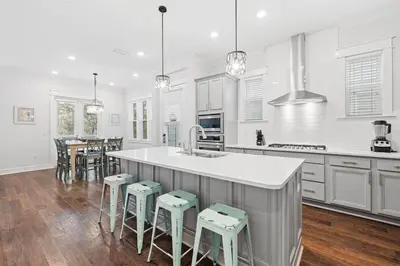 a kitchen with white cabinets and a kitchen island with stools at Serenity Sunset in Inlet Beach