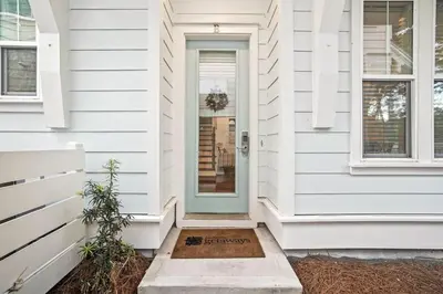 a white house with a door with a welcome sign on it at Serenity Sunset in Inlet Beach