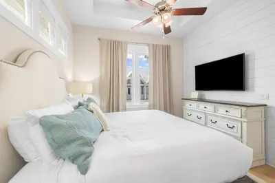 a white bedroom with a white bed and a flat screen tv at Coastal Beauty in Inlet Beach