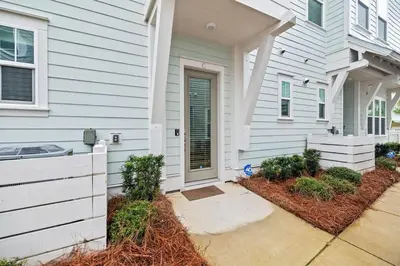 a white house with a door and a yard at Isle be Back in Inlet Beach