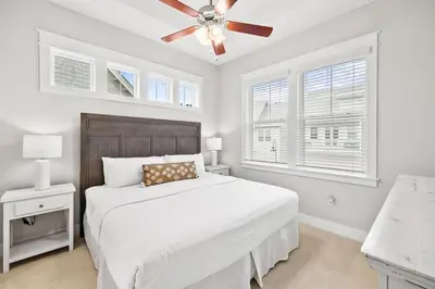 a white bedroom with a bed and a ceiling fan at Isle be Back in Inlet Beach
