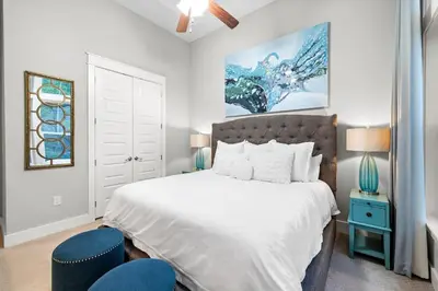 a bedroom with a white bed and a blue chair at Endless Summer in Inlet Beach